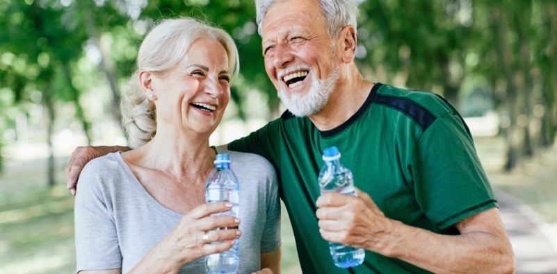 An older couple enjoying the outdoors, both holding a plastic water bottle.
