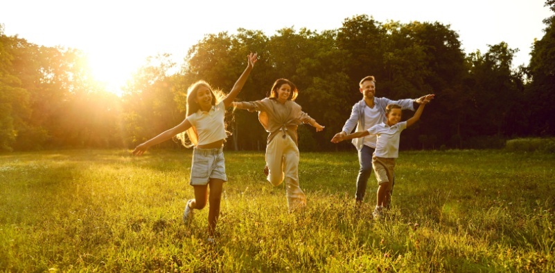 A happy family running and having fun in a park, enjoying a sunny day in nature.